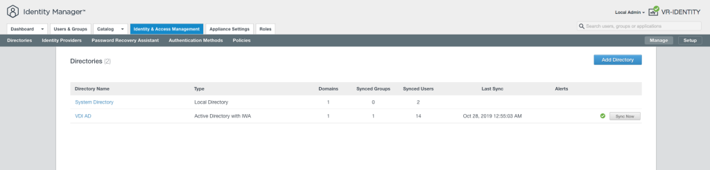 This image displays the "Directories" section of the Identity Manager interface in vRealize Automation 8. It shows a list of two directories: "System Directory" and "VDI AD". The "System Directory" is identified as a Local Directory with 1 domain, 0 synced groups, and 2 synced users, and the "VDI AD" is an Active Directory with Integrated Windows Authentication (IWA) with 1 domain, 1 synced group, 14 synced users, and last synchronized on October 28, 2019, at 12:55:03 AM. Each directory entry provides options like "Sync Now" with a status indicator. The interface also includes navigation tabs such as Dashboard, Users & Groups, Catalog, and Identity & Access Management at the top, along with a search bar and administrative options on the upper right. There's a prominent "Add Directory" button suggesting the ability to add more directories to the system.